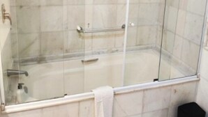 Eine Dusche mit Glaswand und ein weißes Handtuch, das an der Tür hängt.