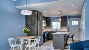 A modern kitchen with dark cabinets, stainless steel appliances, and a central island. - Beach Bliss by 7M Beach (West Bay)