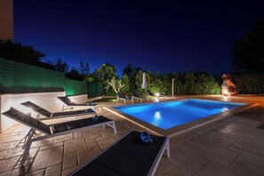 En swimmingpool med liggestole og en bygning i baggrunden.