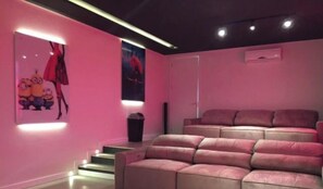 A pink-themed room with a sofa and a poster of Minions on the wall. - Rosa Internacional - Surfland (Garopaba)