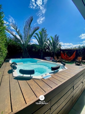 A hot tub on a wooden deck with a clear blue sky and palm trees in the background. - Rosa Internacional - Surfland (Garopaba)
