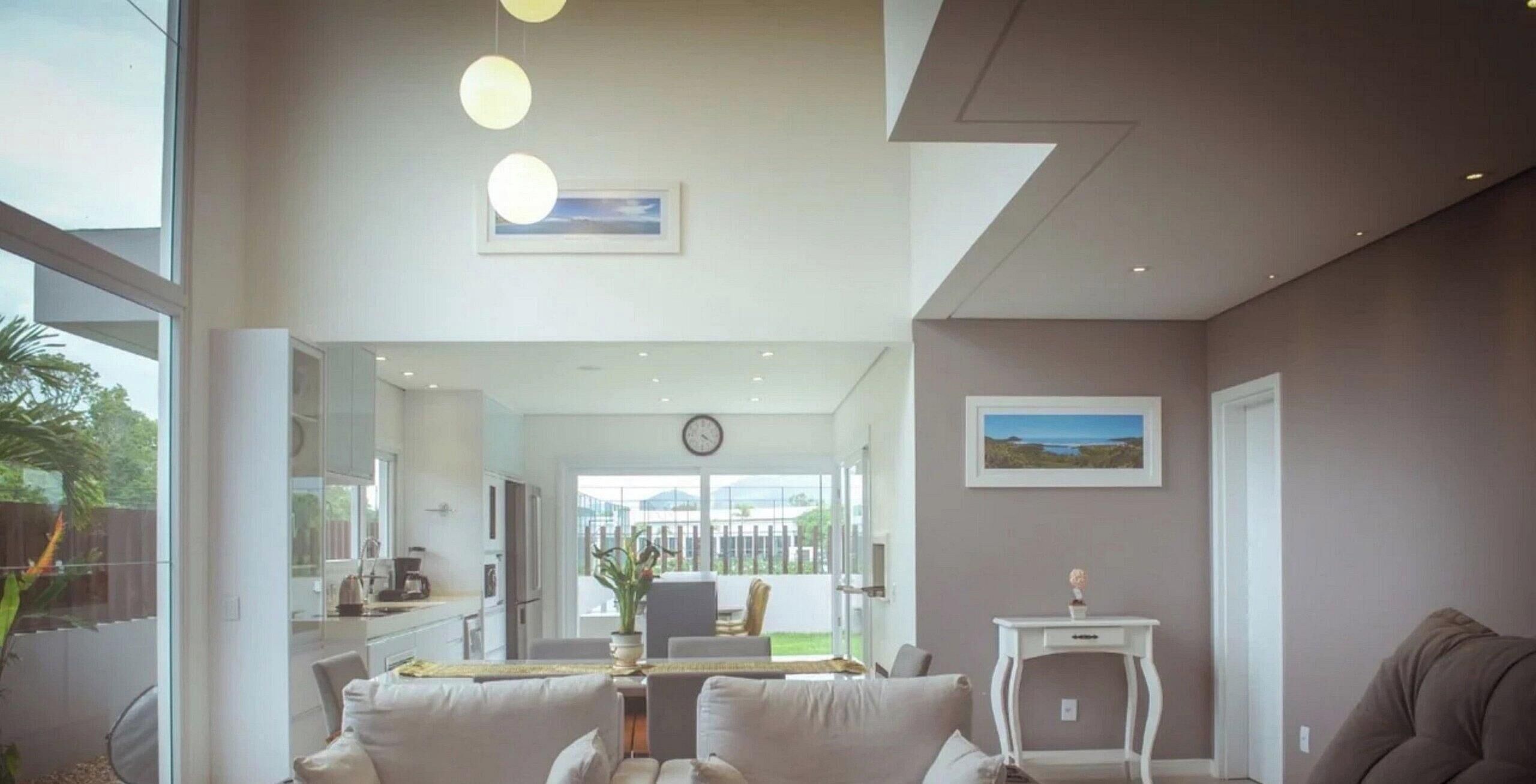 Uma sala de estar moderna com um sofá, uma mesinha e vista para o exterior através de uma porta de vidro.