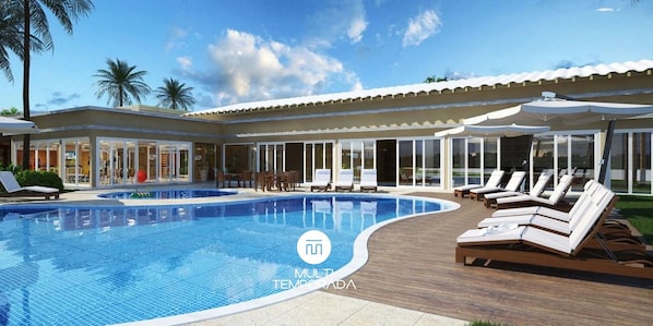 A swimming pool with lounge chairs, a covered patio, and a building with large windows. - Rosa Internacional - Surfland (Garopaba)