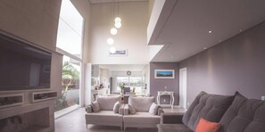 A modern living room with a sofa, TV, and a dining area.
