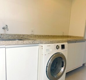 A laundry room with a washing machine, a sink, and a countertop. - Rosa Internacional - Surfland (Garopaba)