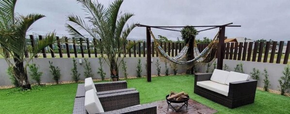A patio with outdoor furniture, a hammock, and a fire pit.