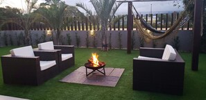 An outdoor seating area with wicker furniture, a fire pit, and a hammock. - Rosa Internacional - Surfland (Garopaba)