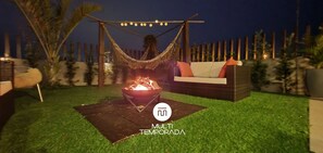 A backyard with a fire pit, a hammock, and outdoor furniture. - Rosa Internacional - Surfland (Garopaba)