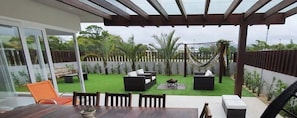 A patio with a glass door, outdoor seating, and a hammock. - Rosa Internacional - Surfland (Garopaba)