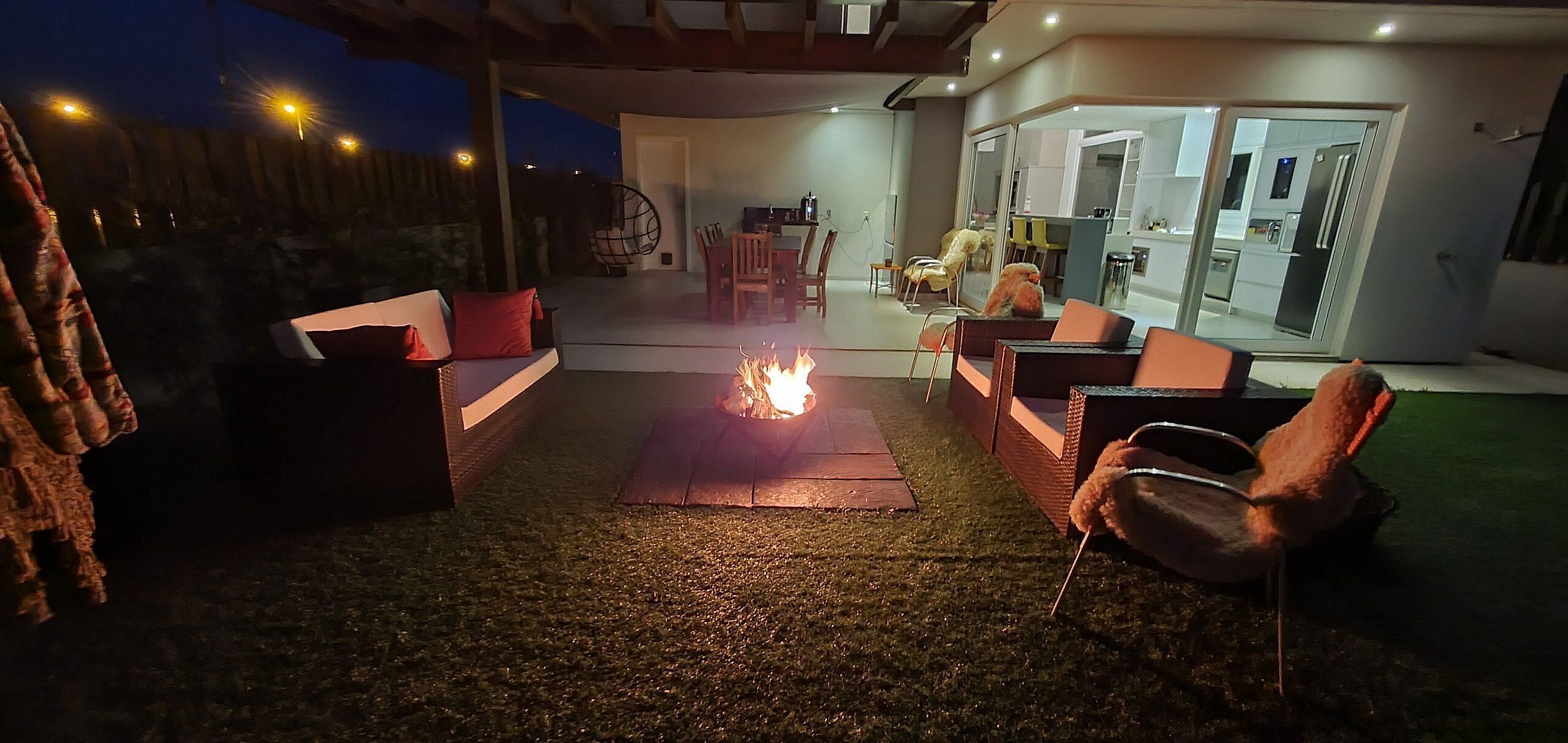 An outdoor patio area with a fire feature, seating, and a view into the house.