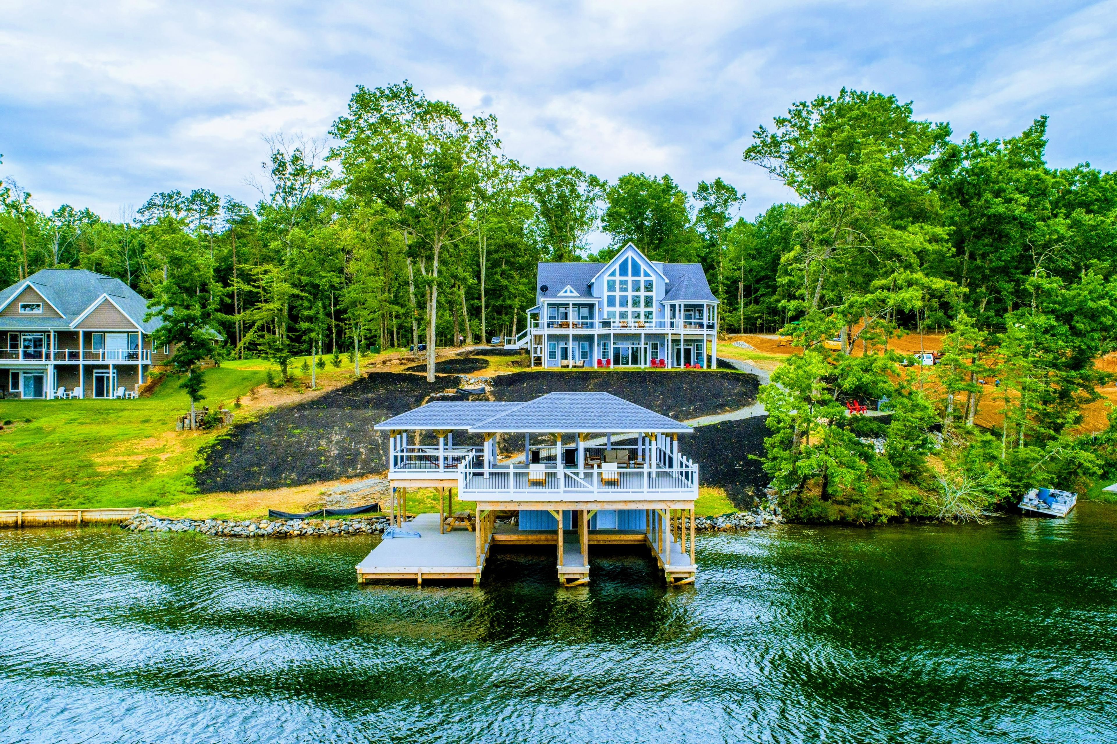 A lakeside property with a main house, a secondary house, and a dock with a cabin.