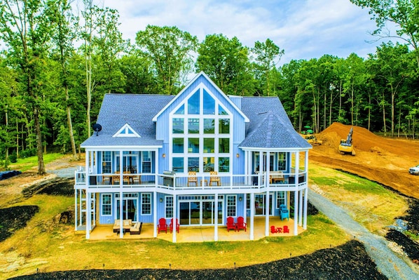 A large two-story house with a balcony, multiple windows, and a covered patio area.