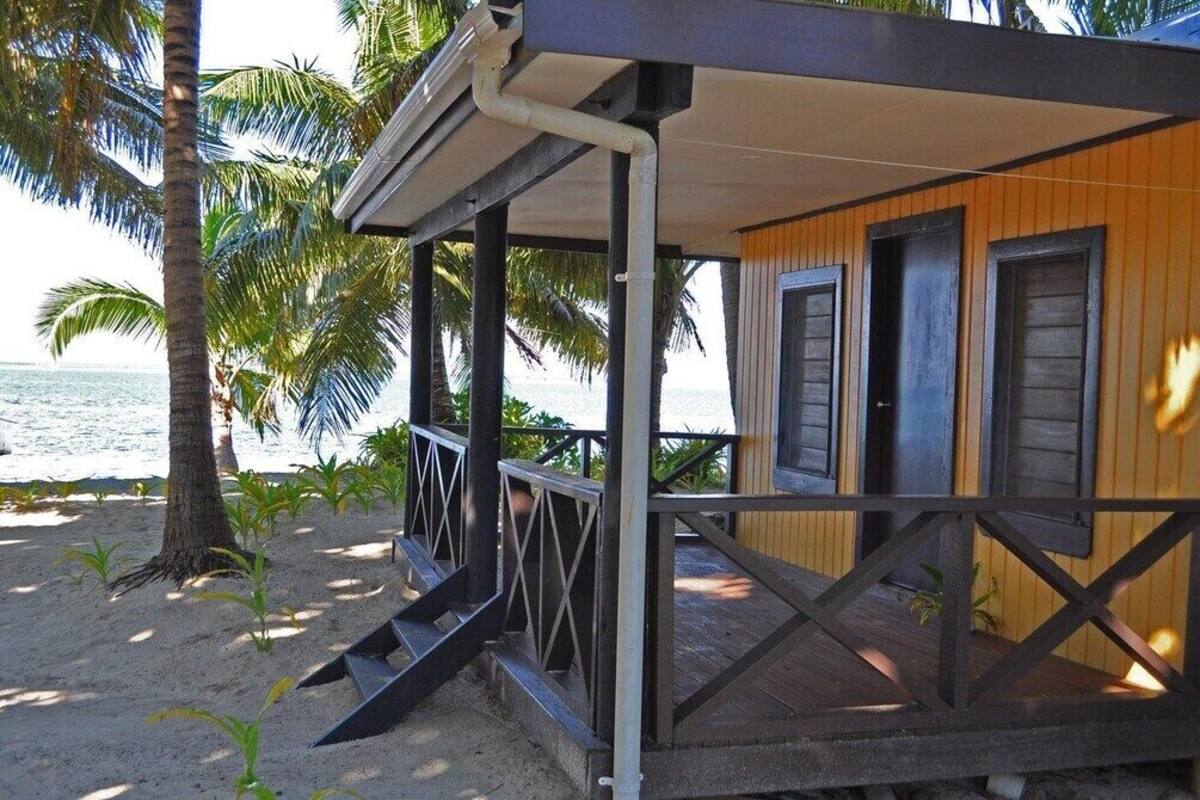 Una casa de playa de madera con un porche cubierto y vista al océano.