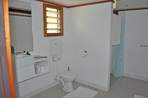 Une petite salle de bain propre, équipée de toilettes, d’un lavabo et d’un miroir.
