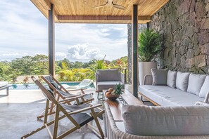 A covered outdoor seating area with a pool, lounge chairs, and a sofa. - Stella Mar Ocean view (Cóbano)