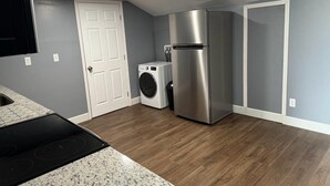 Una cocina con refrigerador de acero inoxidable, lavadora y horno empotrado.