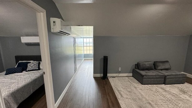 Un dormitorio moderno con cama, sofá gris y un ventanal grande.