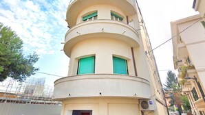 Um edifício com várias andares, fachada curva, varandas e uma entrada central.