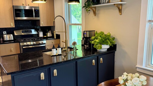 Una cocina moderna con una isla central, electrodomésticos de acero inoxidable e iluminación colgante.