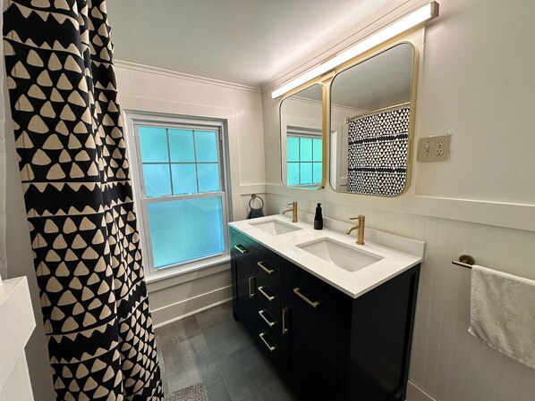 A modern bathroom with two sinks, a large mirror, and a window.