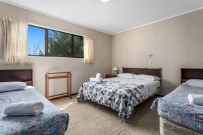 Two single beds with matching headboards and a large window offering a view of the outdoors.
