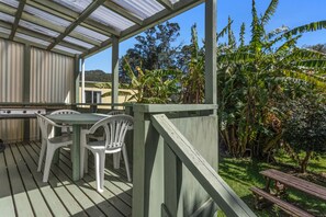 Relax on the deck surrounded by lush greenery, featuring a table and chairs.