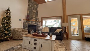 A cozy living room with a fireplace, a Christmas tree, and a stone accent wall. - Apex Mountain ~ Ubuntu at Apex (Keremeos)