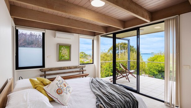 Een slaapkamer met een groot bed, een bankje, een stoel en uitzicht op de omgeving.