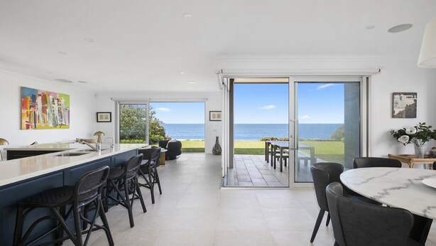 Cocina moderna con vista al mar, que cuenta con un amplio ventanal corredero que da a un área de estar exterior.