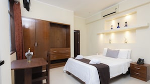 Una habitación de hotel con cama, mesita de noche, silla, armario y escritorio.