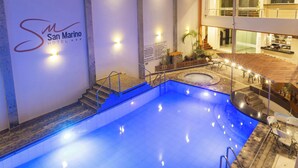 Una piscina de hotel con una zona de estar hundida, una escalera que lleva al nivel superior y un letrero del Hotel San Marino.