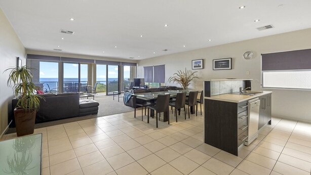A modern kitchen with a central island, a dining area with a glass table, and a living space with a sofa and large windows overlooking the ocean. - The Cove, Port Hughes (Port Hughes)