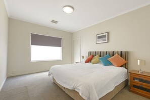 A bedroom with a large bed, a window with blinds, a bedside table with a lamp, and a framed picture on the wall. - The Cove, Port Hughes (Port Hughes)