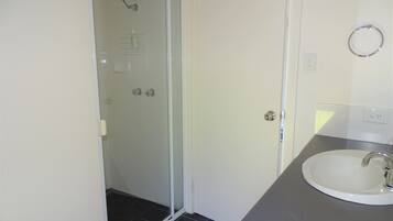 A bathroom with a glass-enclosed shower, a white sink, and a towel rack.