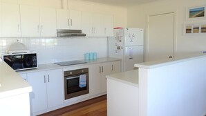 A modern kitchen with white cabinets, a stainless steel range hood, a built-in oven, a microwave, and a refrigerator. - Shell Seeker, Moonta Bay (Moonta Bay)