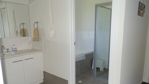 A modern bathroom with a white sink, mirror, and towel rack.