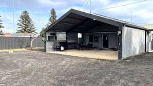 Un bâtiment en métal doté d’un patio couvert, d’un barbecue et de sièges extérieurs.
