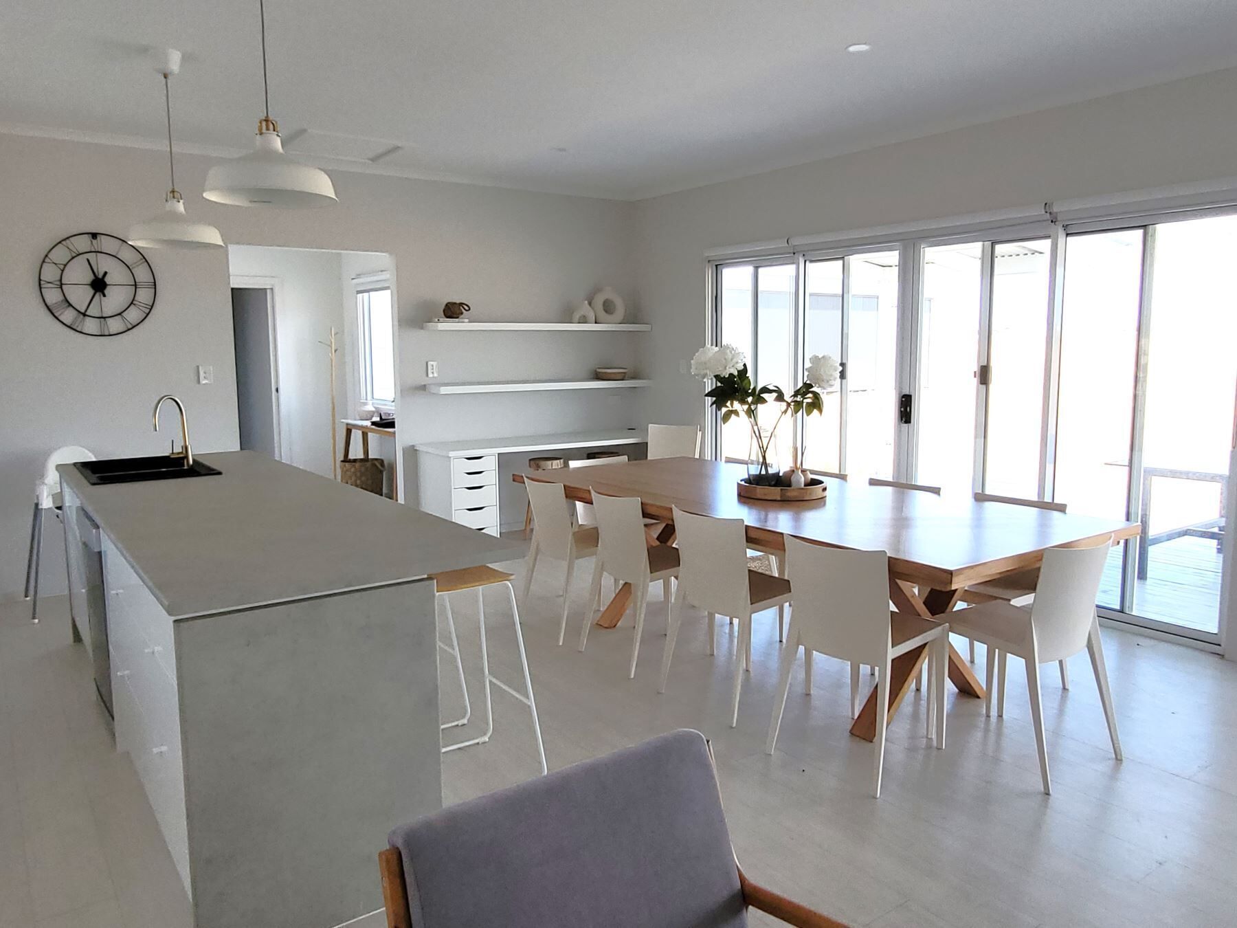 Une cuisine moderne avec un îlot central, des chaises blanches et une table à manger.