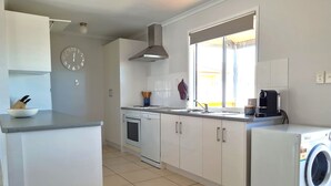 Een moderne keuken met witte kasten, een inbouwoven, een spoelbak en een wasmachine.