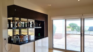 Une cuisine moderne avec un coin bar, de grandes portes-fenêtres coulissantes et une vue sur l’extérieur.