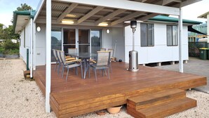 Un espace extérieur abrité doté d’une terrasse en bois, d’une table avec des chaises et d’un chauffage d’extérieur.