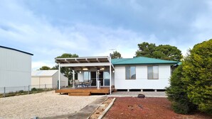 Une maison de plain-pied dotée d’un patio couvert, d’une cour clôturée et d’un petit jardin.