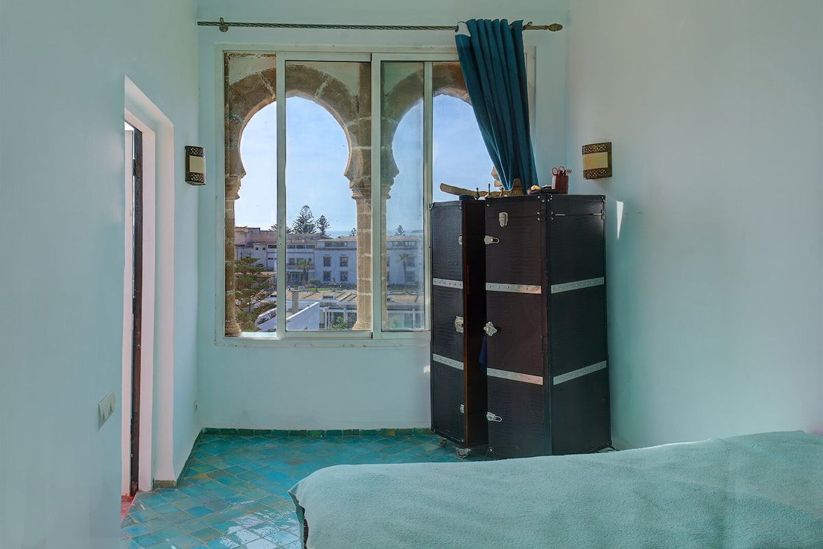 A room with a large arched window, a wardrobe, and a bed.