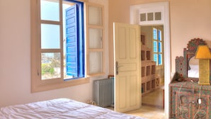 Une chambre à coucher avec un lit, un radiateur, une armoire et une fenêtre avec des volets bleus.