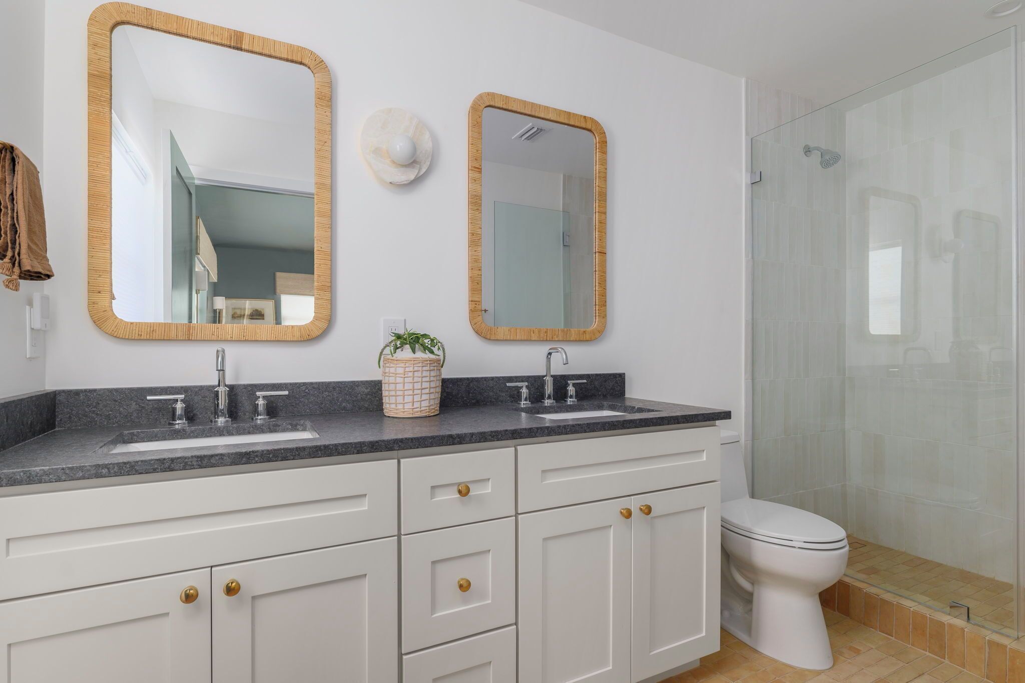 A bathroom with a white vanity, two mirrors, a sink, and a toilet.