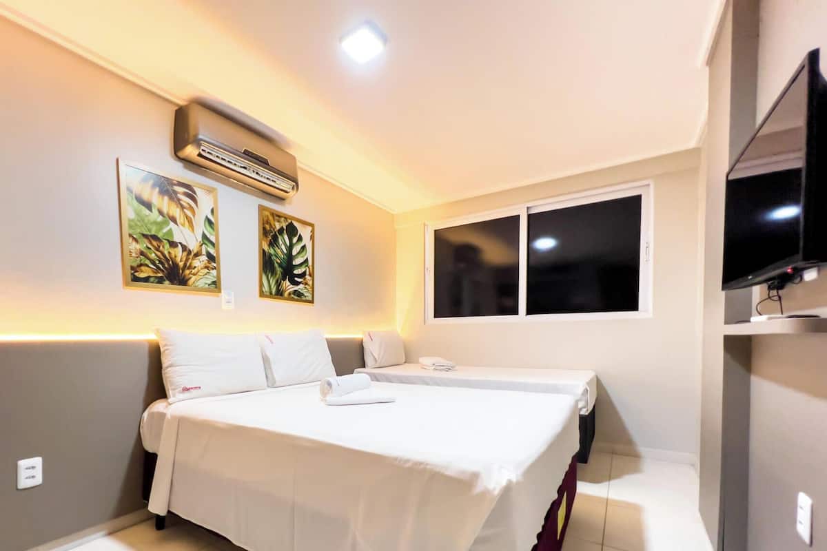 Een hotelkamer met een bed, een televisie en twee wandgemonteerde airconditioners.