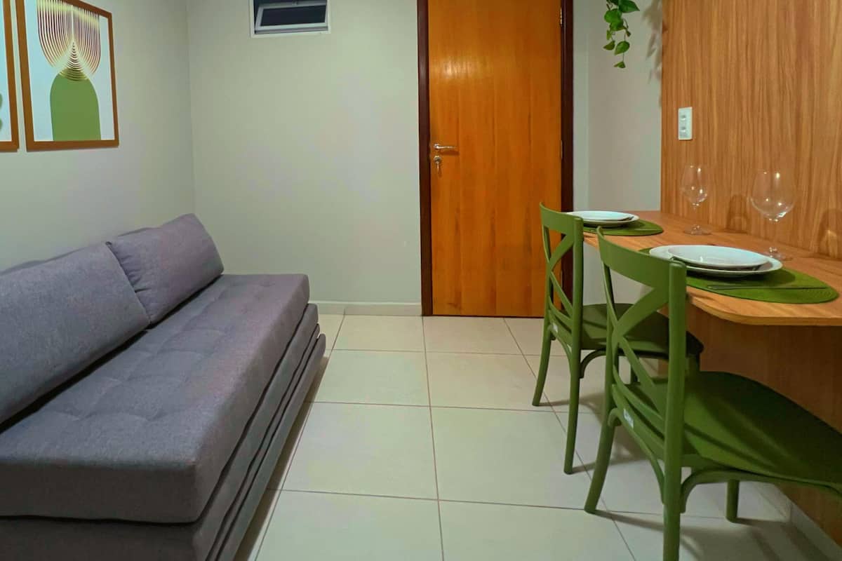 Een woonkamer met een bank, een eettafel met stoelen, en een houten deur.