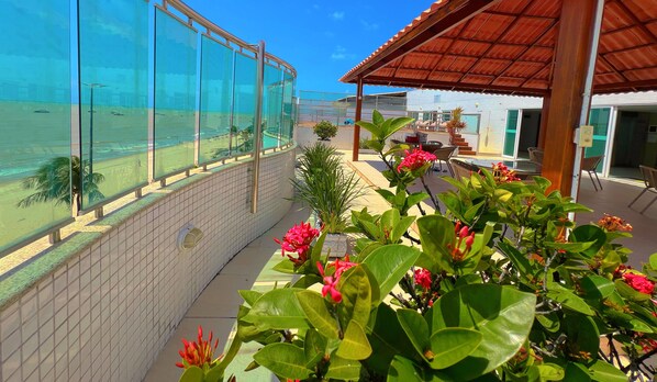 Enjoy the serene ocean views from this hotel's spacious balcony, surrounded by lush greenery and a sandy beach.