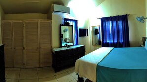 A bedroom with a bed, a dresser, a mirror, an air conditioner, and a TV. - Hidden Gem, Cozy 2-bedroom house with WiFi, AC, Private Pool In Portmore (Portmore)