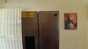 A stainless steel refrigerator with a 10-year warranty sticker, a small control panel, and a freezer compartment. - Hidden Gem, Cozy 2-bedroom house with WiFi, AC, Private Pool In Portmore (Portmore)
